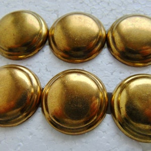 May include: A set of six circular, dome-shaped buttons with a metallic gold finish. Each button features a smooth, rounded surface with a raised edge, presenting a uniform appearance across all pieces in this collection of sewing fasteners.