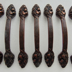 May include: Set of eight antique-style cabinet pulls with a bronze finish. Each pull features a detailed design of grapes and leaves.