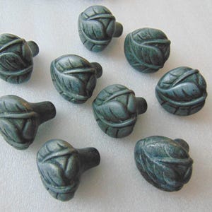May include: Ten teal green ceramic cabinet knobs with a leaf design.