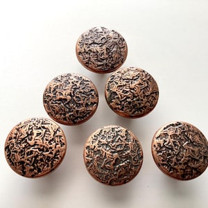 May include: Six bronze-colored cabinet knobs with a textured, organic design. The knobs are round and have a dark brown, almost black, textured surface. The knobs are arranged in a circular pattern.