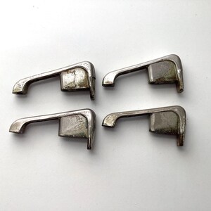 May include: Four vintage metal drawer pulls with a curved handle design. The pulls are silver-toned with signs of wear and age, suggesting they are antique or reclaimed hardware. They are arranged on a white background.