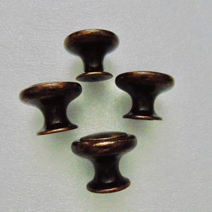 May include: Four antique bronze cabinet knobs with a round top and a short, round base.