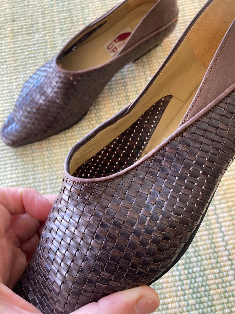 Puede incluir: Un par de bailarinas de cuero trenzado marr&oacute;n. Los zapatos tienen una punta afilada y un tac&oacute;n bajo. El interior del zapato es de color beige claro. Los zapatos est&aacute;n en buen estado y parecen ser vintage.