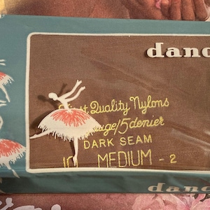May include: Vintage "dancette" nylon stockings in original packaging. The box is teal with illustrations of ballerinas in white and red tutus. The center panel is brown with the brand name and product details.