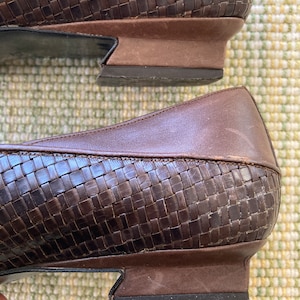 Puede incluir: Primer plano de dos zapatos de cuero marr&oacute;n. Los zapatos tienen un patr&oacute;n tejido en la parte superior y un tac&oacute;n bajo. Las suelas son de color marr&oacute;n oscuro y los zapatos parecen desgastados.