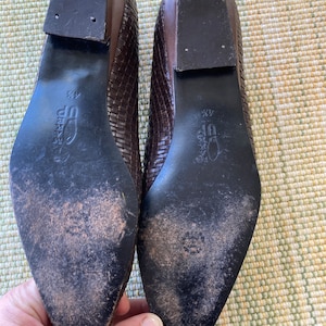 Puede incluir: Par de bailarinas de cuero marr&oacute;n tejido con puntera cuadrada. Las suelas son oscuras con desgaste y los tacones son de color marr&oacute;n oscuro. Los zapatos son de talla 4 1/2.