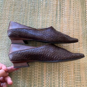 Puede incluir: Un par de zapatos planos de cuero marr&oacute;n tejido con puntas puntiagudas. Los zapatos tienen un tac&oacute;n bajo y un ribete de cuero marr&oacute;n en contraste. El patr&oacute;n tejido crea una apariencia texturizada.