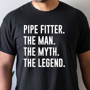 May include: A black t-shirt with white text that reads "PIPE FITTER. THE MAN. THE MYTH. THE LEGEND."