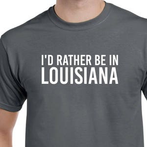 May include: A dark gray t-shirt with the text "I'd rather be in Louisiana" printed in white.