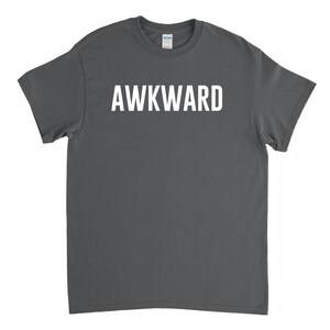 May include: A dark gray t-shirt with the word "AWKWARD" printed in white on the front.