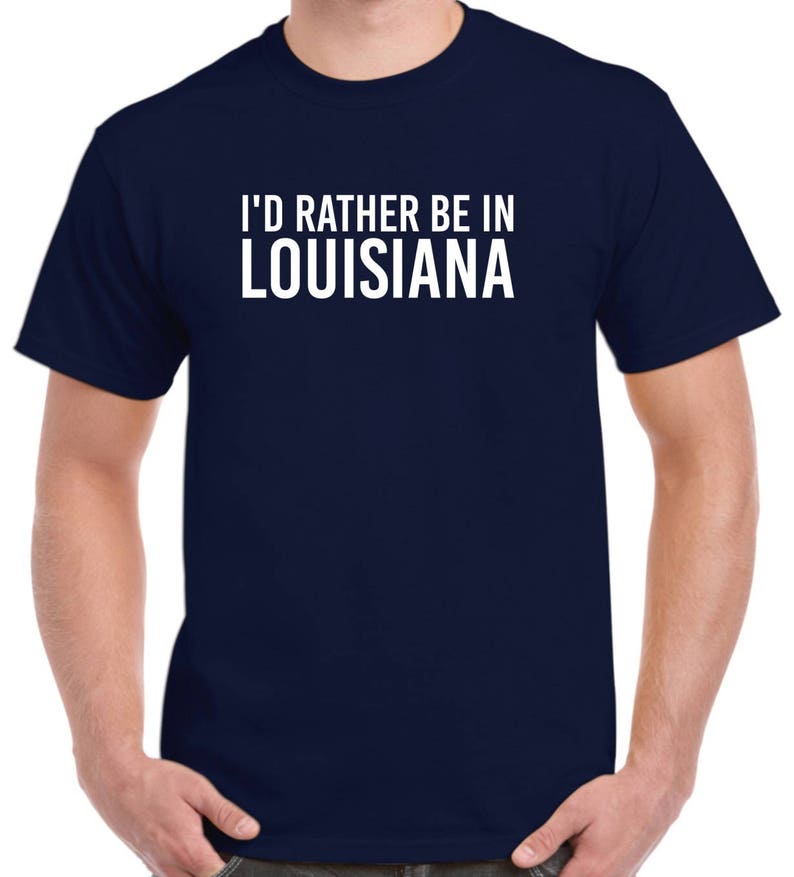 May include: A navy blue t-shirt with white text that reads "I'd rather be in Louisiana".