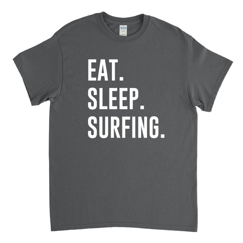 Puede incluir: Una camiseta gris oscuro con texto blanco que dice "EAT. SLEEP. SURFING."