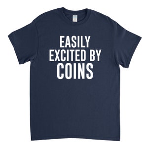 K&ouml;nnte beinhalten: Ein marineblaues T-Shirt mit wei&szlig;em Text, der "EASILY EXCITED BY COINS" lautet.