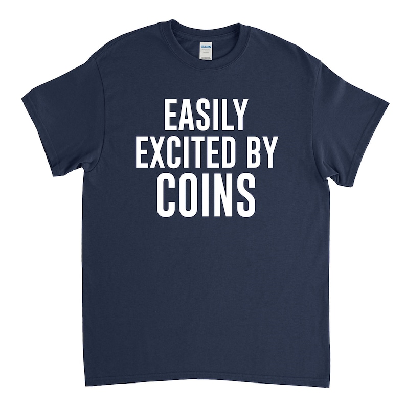 K&ouml;nnte beinhalten: Ein marineblaues T-Shirt mit wei&szlig;em Text, der "EASILY EXCITED BY COINS" lautet.