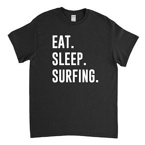 Puede incluir: Camiseta negra con texto blanco que dice "EAT. SLEEP. SURFING."