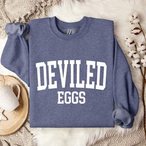 May include: A heather blue sweatshirt with the text "DEVILED EGGS" in white block letters.