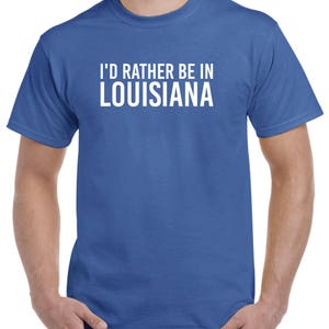 May include: A royal blue t-shirt with white text that reads "I'd rather be in Louisiana".