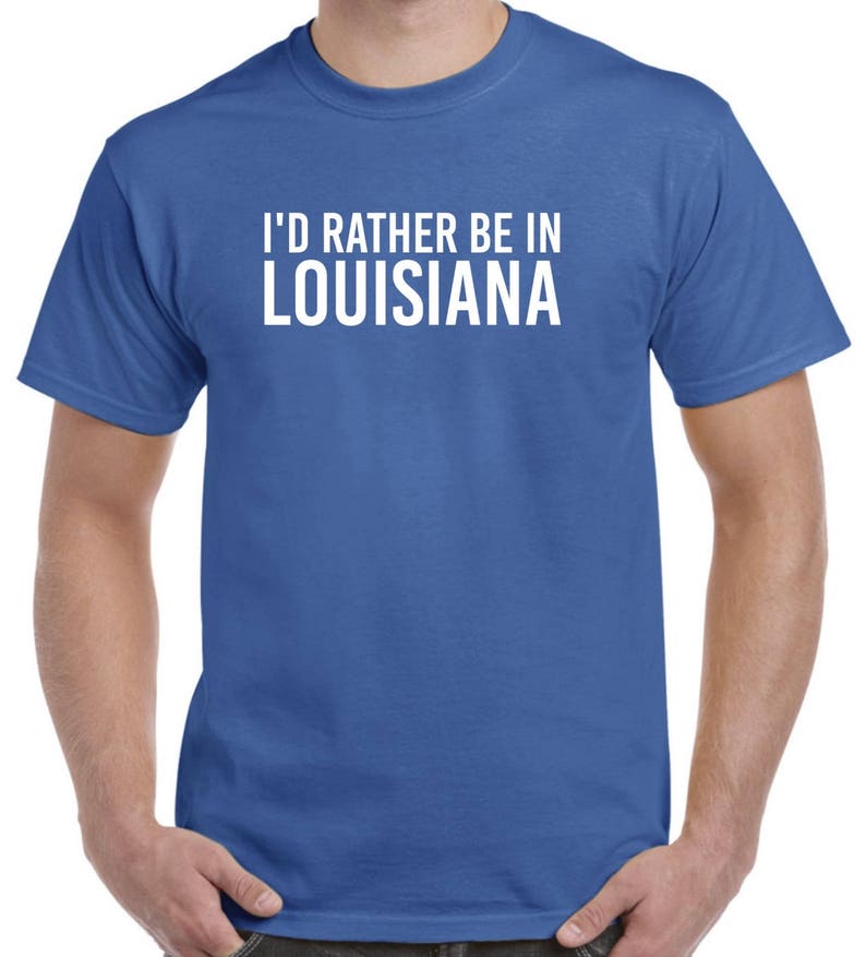 May include: A royal blue t-shirt with white text that reads "I'd rather be in Louisiana".