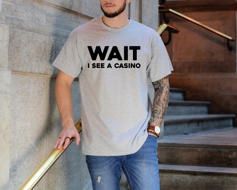 Pu&ograve; includere: Una maglietta grigia con testo nero che dice "WAIT I SEE A CASINO".