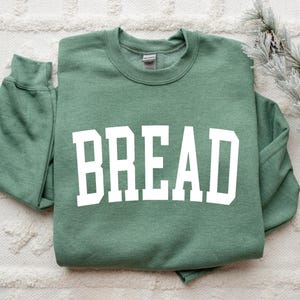 May include: A green sweatshirt with the word "BREAD" printed in white on the front.