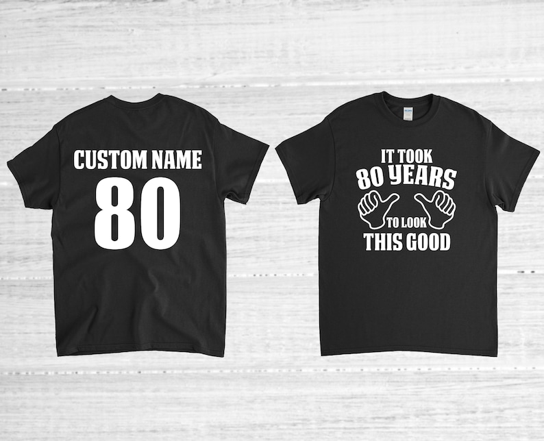 May include: Two black t-shirts. One shirt has the text "CUSTOM NAME 80" on the back. The other shirt has the text "IT TOOK 80 YEARS TO LOOK THIS GOOD" with two thumbs up on the front.