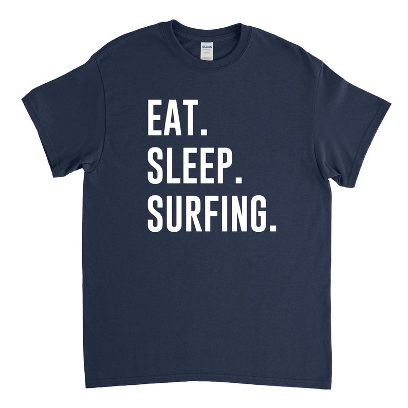 Puede incluir: Una camiseta azul marino con texto blanco que dice "EAT. SLEEP. SURFING."