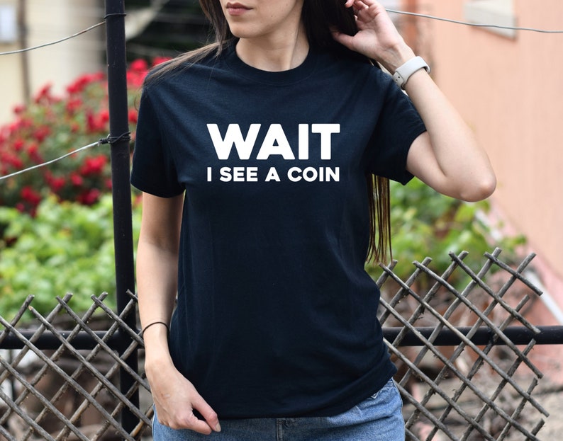 May include: A black t-shirt with white text that reads "WAIT I SEE A COIN".