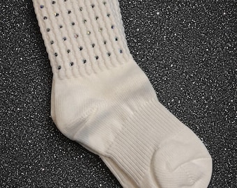 May include: A white ankle sock featuring a ribbed cuff embellished with small, clear, reflective rhinestones arranged in vertical rows. The sock has a smooth, plain foot section and a thick, textured knit construction around the upper ankle area.