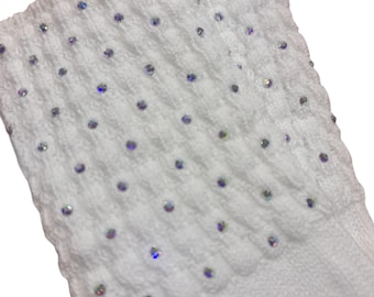 May include: Close-up of a white knitted sock with a cuff adorned with iridescent rhinestones. The cuff features a textured pattern, and the sock appears soft and comfortable. The overall aesthetic is elegant and suitable for special occasions.