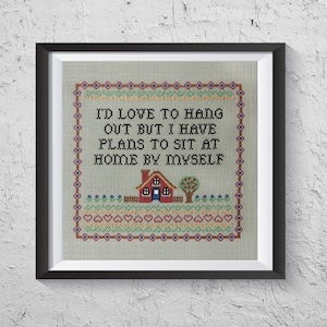 May include: Cross-stitch embroidery featuring a red house, green tree, and the text "I'd love to hang out but I have plans to sit at home by myself."