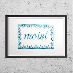 May include: A framed cross-stitch embroidery with a blue and green border and the word "moist" stitched in blue thread.