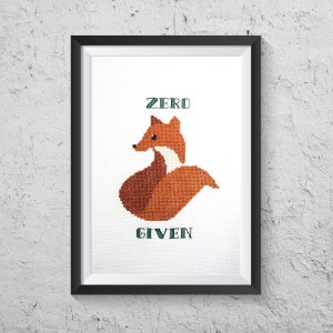 以下が含まれることがあります： 緑色の文字「ZERO GIVEN」と赤いキツネが描かれた、額装されたクロスステッチのデザインです。