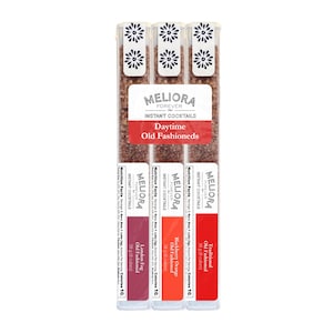 May include: Three tubes of Meliora Forever Instant Cocktails, Daytime Old Fashioneds. Each tube is labeled with a different flavor: London Fog, Blackberry Orange, and Traditional. The tubes are clear with white floral designs on the top.