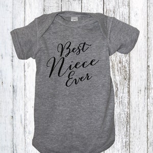 May include: Gray baby onesie with black text that reads "Best Niece Ever".