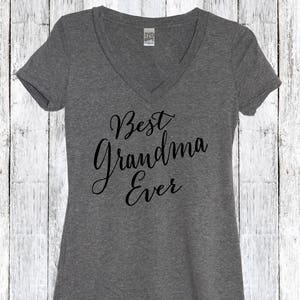 May include: Gray V-neck t-shirt with the text "Best Grandma Ever" in black cursive lettering.