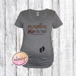 May include: Gray maternity shirt with a V-neck and the text "pumpkin pie for two - Arriving March 2022" in brown and orange.  Two black footprints are below the text.