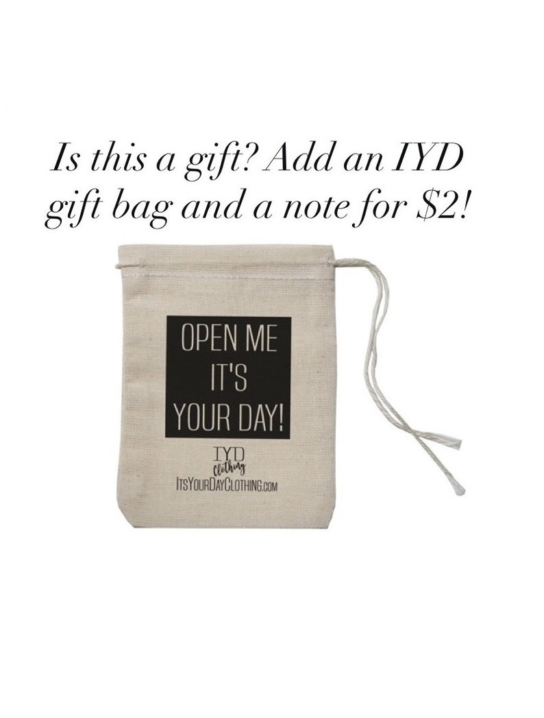 May include: A white cotton drawstring bag with black text that reads "Open Me It's Your Day!" and the logo "TYD Clothing ItsYourDayClothing.com".