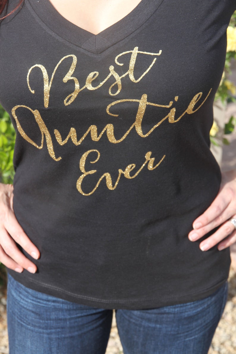 May include: Black v-neck t-shirt with gold glitter lettering that reads "Best Auntie Ever".