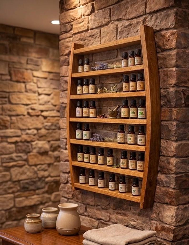 May include: A wall-mounted wooden shelf with a curved frame holding multiple small amber glass bottles of essential oils. The shelf features six horizontal tiers, with dried lavender sprigs and a small mortar and pestle placed among the bottles.