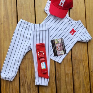 May include: A baseball uniform set for a child, featuring a white and black striped jersey with a red letter "M" on the front, matching pants, a red baseball cap with a white letter "M", and a red belt.
