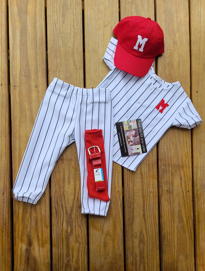 May include: A white and blue striped baseball uniform with a red baseball cap, a red belt, and a red letter "M" on the shirt and cap. "Thank you for all you do" is printed on a small card.