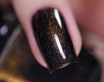 May include: Close-up of a fingernail with dark brown nail polish with gold and green glitter.