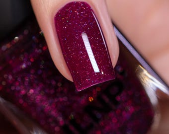 May include: A close-up of a fingernail painted with a deep red nail polish with a fine white glitter finish. The nail polish bottle is visible in the background with the brand name "ILNP" printed on the label.