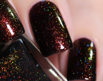 May include: Close-up of dark nail polish with a black base and iridescent glitter. The glitter reflects multiple colors, including red, green, and blue. The polish is applied to the fingernails, with a glossy finish.