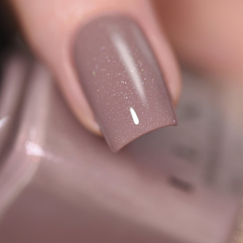 Peut inclure: Gros plan sur un ongle avec un vernis &agrave; ongles brun clair avec une finition scintillante.