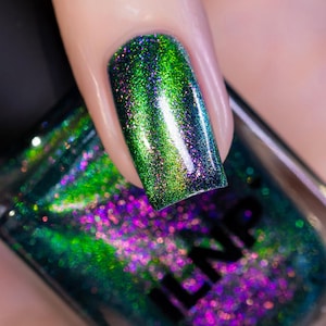 May include: Close-up of a fingernail painted with iridescent nail polish. The polish shifts between green, purple, and blue hues, with a glittery finish. The nail polish bottle is visible in the background.