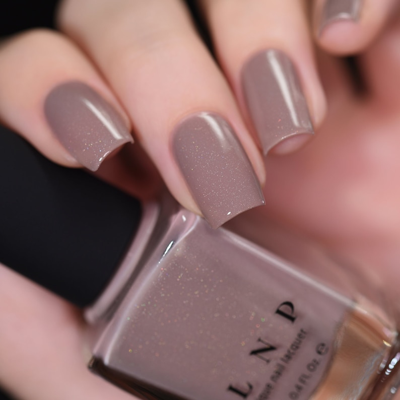 Peut inclure: Un flacon de vernis &agrave; ongles brun clair avec une finition scintillante. Le flacon est &eacute;tiquet&eacute; "LIN.D" et "Nail Polish Lacquer".