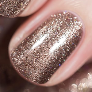 May include: Close-up of a fingernail with a sparkly, metallic brown nail polish.