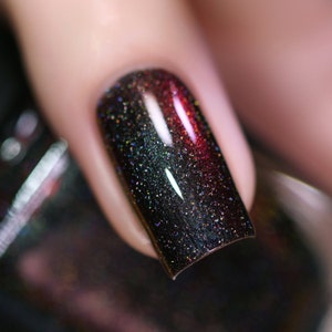 May include: Close-up of a fingernail with dark green and red nail polish with a shimmery finish.
