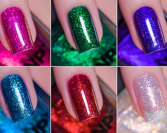 Puede incluir: Seis botellas de esmalte de uñas con diferentes colores y acabados de purpurina. Los colores son rosa, verde, azul, turquesa, rojo y blanco.